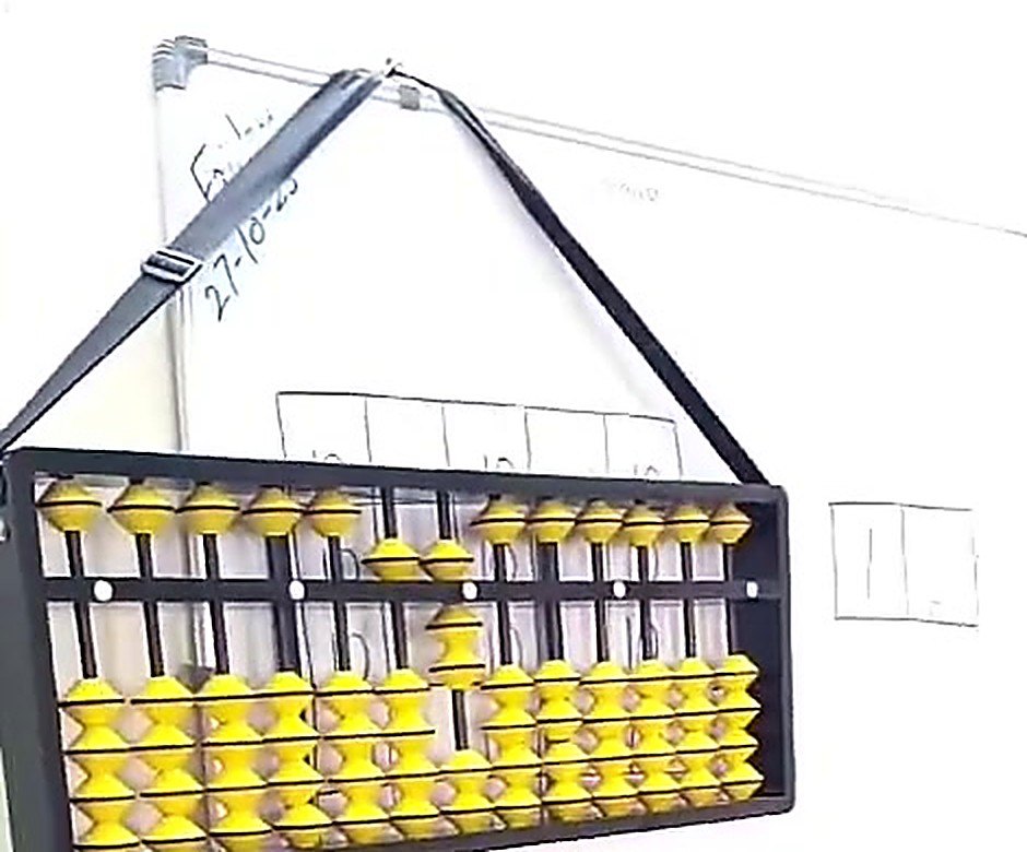 Large teaching abacus hanging on a classroom wall, used for the weekly abacus batch