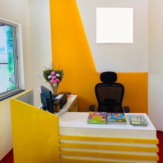 Preschool reception desk with an empty signboard on the wall and activity books laid out for visiting parents